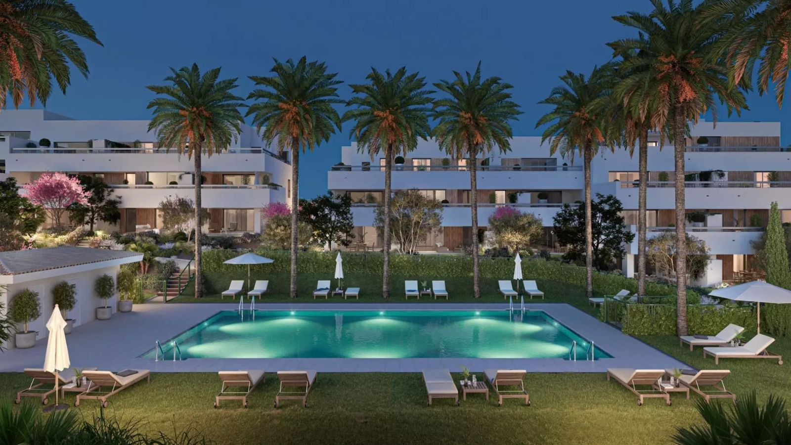 Moderne Wohnungen mit Pool und Palmen in Sunset Bay Estepona in der Dämmerung.